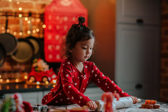  little asian girl roll out the dough for Christmas cookies on the kitchen