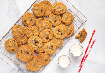 Overhead view of homemade chocolate chip cookies with two glasses of milk and drinking straws, copy space