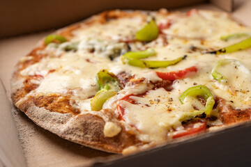 Vegetarian pizza with paprika on wholegrain dough in a cardboard box for delivery