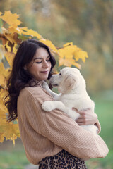Beautiful brunette woman with her golden retriever puppy, autumn beautiful colors, emotions