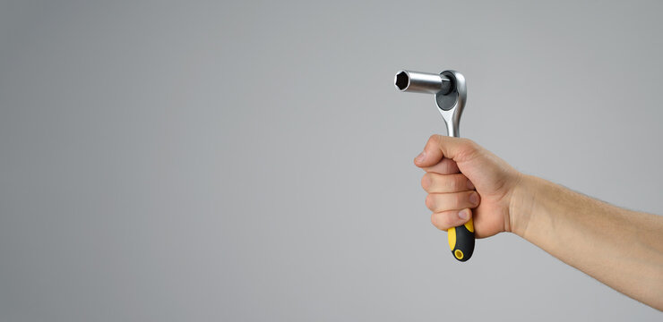 Male hand holds ratchet socket wrench to repair something. Do it yourself. Copyspace