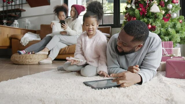 X'mas Happy african family father and cute daughter having fun with smart tablet computer at home, black parents and little children using digital gadget teach how to draw making sending e-card.