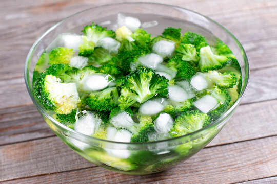 Blanched broccoli cabbage cooling down in icy water in a bowl on table