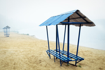 Blue benches on a deserted beach in the fog