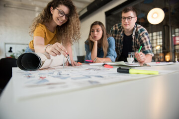 Group of designers discussing over blueprint