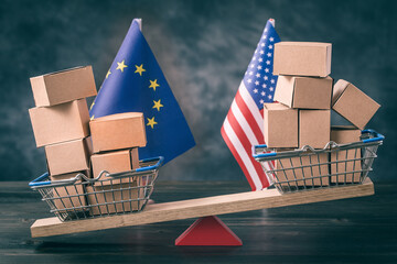 Filled shopping basket and cart with US and EU flags on seesaw. Trade balance concept