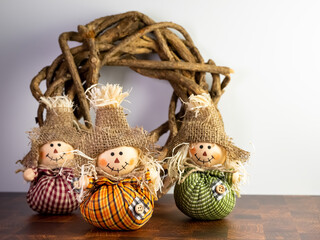 Three Mini Stuffed Scarecrows with Plaid Clothes and a Burlap Hat with a Wooden Wreath, perfect for Halloween and Fall or Thanksgiving decor.