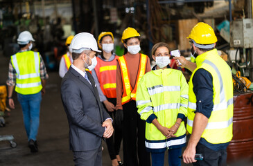 Obraz premium Temperature measurement with employee temperature meter before entering work at factory. Professional engineering team.