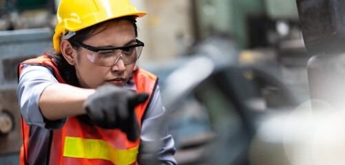 Obraz premium Woman worker wearing safety goggles control lathe machine to drill components. Metal lathe industrial manufacturing factory