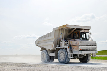 Obraz premium Big yellow dump truck working in the limestone open-pit. Loading and transportation of minerals in the chalk mining quarry. Belarus, Krasnoselsk, in the largest i chalk deposit, quarry 