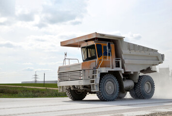 Fototapeta premium Mining truck transports chalk from open pit to an industrial plant for the needs of the construction industry and world markets. Loading and transportation of minerals in the limestone mining quarry