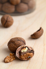 brown walnuts in shells on a wooden table and in a glass jar. close up nuts on a background. copy space. vertical