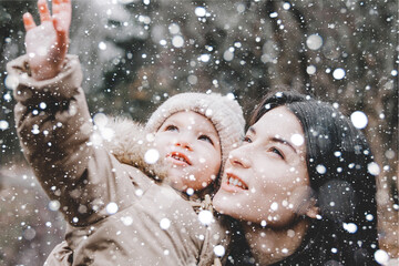 Beautiful young mom and her little cute daughter have fun outdoors in winter. Happiness to spend time together. Family concept.