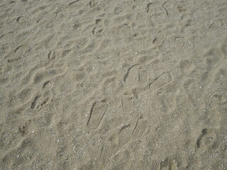 Footprints on dry sand. There are many footprints on the floor. Some people wear shoes and others do not wear walking shoes on the beach.

