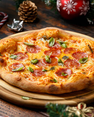 Christmas Salami, Pepperoni Pizza with decoration, gifts, green tree branch on wooden rustic table.