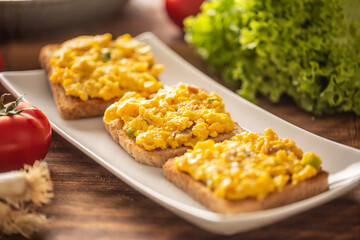 Scrambled eggs on toasts served on a plate