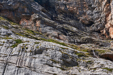 sheer rock wall with a small waterfall flowing down it