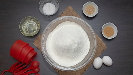 tazón de harina y otros ingredientes para preparar masa para hornear, huevos, levadura, sal, azúcar, aceite tazas para medir