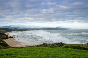 green grassy cliffs drop down to the ocean coast and a large beautiful sandy beach