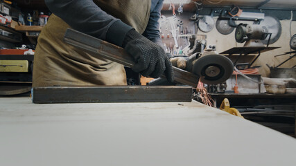 A man in gloves cuts metal with a circular saw, a lot of sparks. The working process