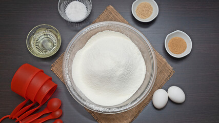 tazón de harina y otros ingredientes para preparar masa para hornear, huevos, levadura, sal, azúcar, aceite tazas para medir
