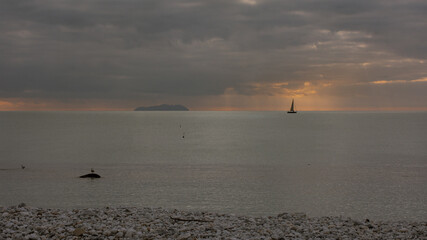 barca a vela con isola illuminata dai raggi del sole al tramonto