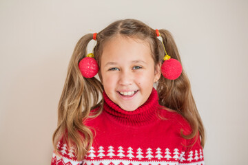 Girl in Christmas sweater with Christmas ornaments on her ponytails