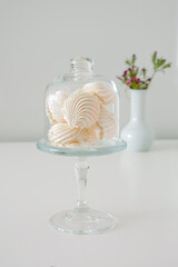 small white merinques in glass jar on a white background
