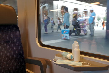 New normal commuting with face masks and hand sanitizers displayed in train carriage. Train is at station and the passengers wearing face masks go in trying to keep safe distance in coronavirus time. 