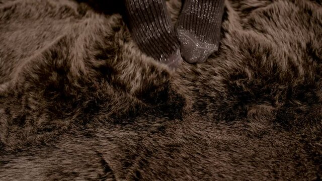Frau in Glitzer Socken genie&szlig;t und streichelt sich in einem Schafsfell  