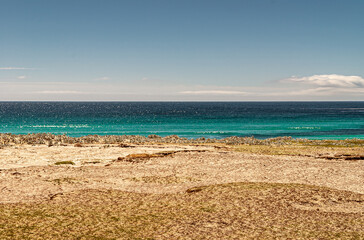 Volunteer Beach, Falkland Islands, UK - December 15, 2008: Wide shot of azure and blue Atlantic ocean behind yellow sand and under light blue cloudscape.