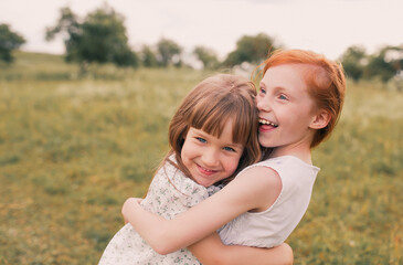 two little girls sisters play and have fun on the grass holding hands in light dresses.Summer, Sunny weather in a good mood