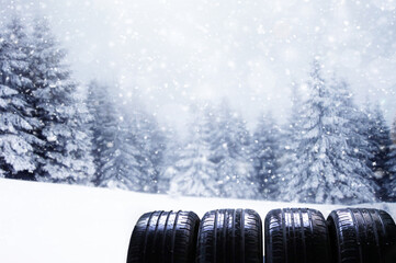 Close up of four winter car tire with blurred trees background and snow flakes. Change used tires for new one. High quality photo
