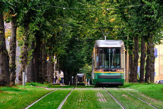 Helsinki, Finland - September 20, 2020: The tram is moving on the Makelankatu in Vallila district. The street like a green tunnel.