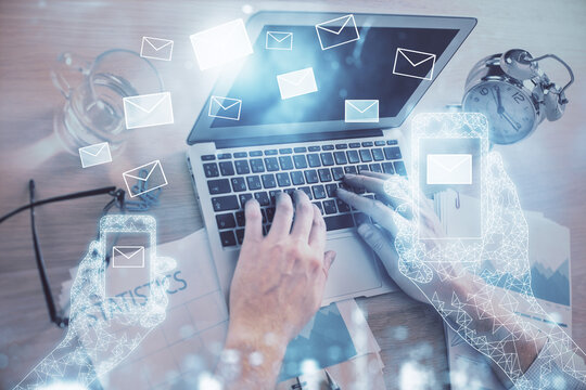 Envelop hologram drawing with businessman working on computer on background. Electronic mail concept. Double exposure.