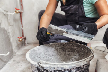 Woman hand of worker applies plaster on cement wall trowel for house construction