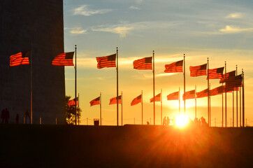 Silhouettes and U.S. national flags at Washington Monument grounds during sunset - Washington D.C....