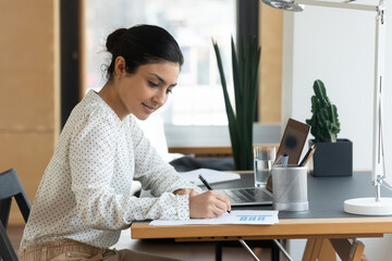 Side view concentrated young professional indian mixed race female analyst working with marketing...