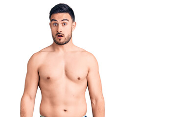 Fototapeta premium Young handsome man wearing swimwear in shock face, looking skeptical and sarcastic, surprised with open mouth