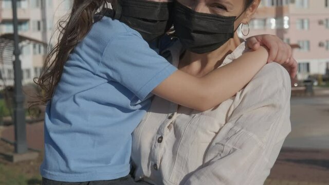 Masked family. Life in protective masks. Mother holds her daughter in her arms in protective masks.