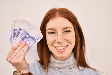 Young irish teenager girl smiling happy holding swedish krone banknotes standing at the city.