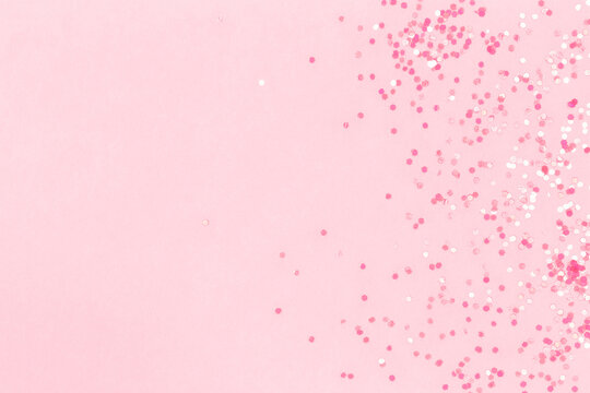 Pink background with sequins. Suitable for backdrop for your design. Top view, copy space.