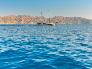 Fototapeta na wymiar alone huge sail yacht rides by sea in morning lights under blue sky