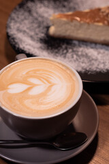 Cup of latte with curd cheesecake on dark wooden background