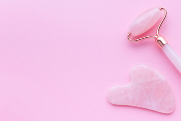 Pink jade roller and gua sha tool on pastel background. Trendy beauty tool. Minimal composition. copy space