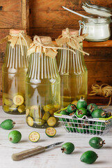 Homemade feijoa compote. Delicious healthy vitamin drink. Jars and fresh berries on a light wooden table. Selective focus