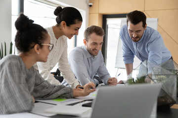 Group of happy millennial multiracial colleagues involved in working process, doing project paperwork together, analyzing marketing reports, discussing development growth strategy in modern office.