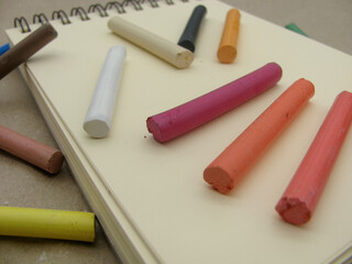 Multi-colored dry pastels on an empty sketchbook sheet for drawing
