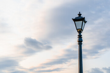 Fototapeta na wymiar Street light with classic lamppost against a cloudy sky. Vintage style lamp post outdoors with copy space