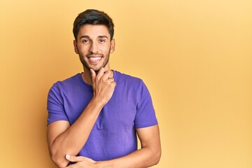 Young handsome man wearing casual clothes smiling looking confident at the camera with crossed arms and hand on chin. thinking positive.